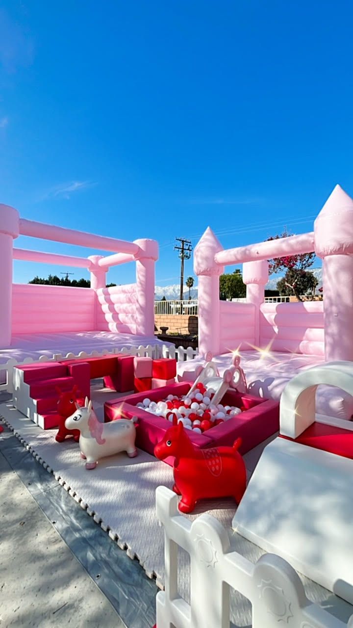 Pink and white outdoor lounge under a blue sky, with red chairs and tables on a snowy terrace.