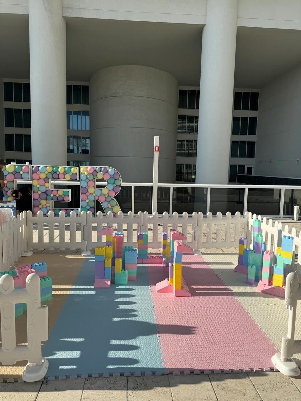 Colorful block play area with a picket fence in front of a building with large columns