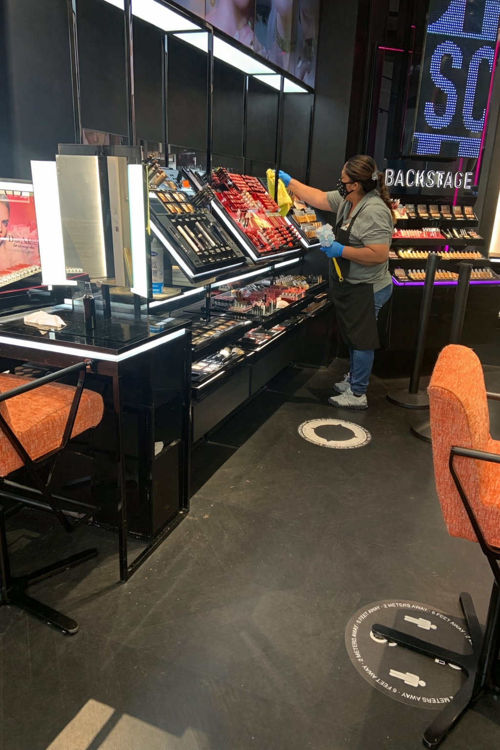 Person browsing cosmetics at a store display with a mirror and colorful makeup products.