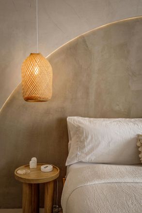A textured woven pendant lamp hangs above a small wooden side table.