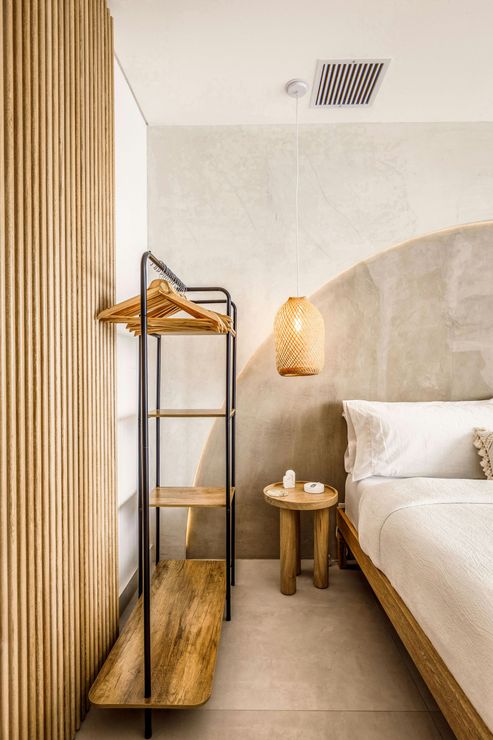 A bedroom with a textured concrete wall and a wooden bedside table. A bedroom with a textured concrete wall and a wooden bedside table.