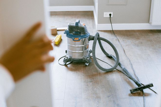 A shop vacuum sits on a wooden floor in a room. A shop vacuum sits on a wooden floor in a room.