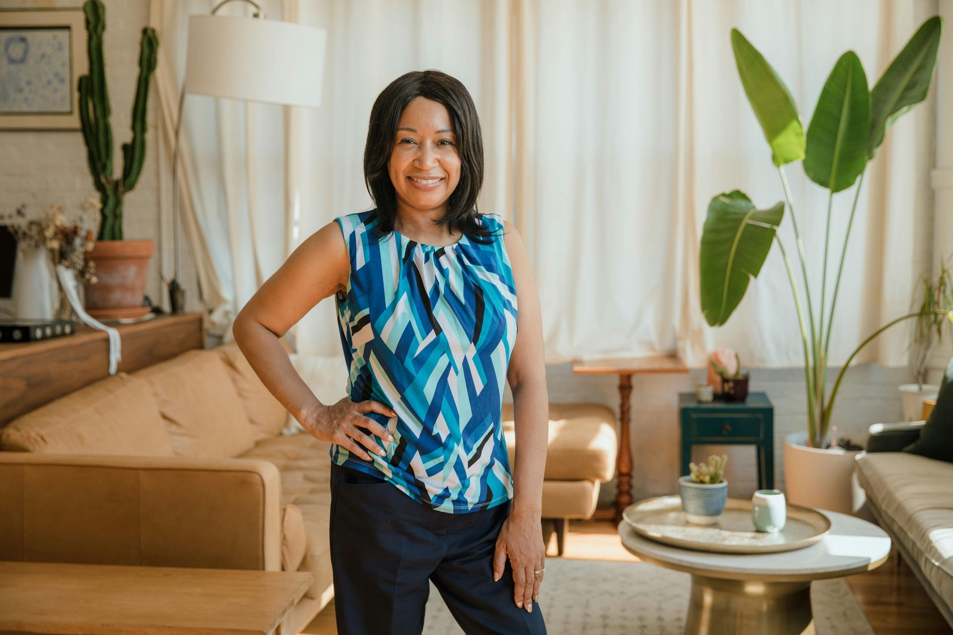 A smiling person standing in a living room with a couch. A smiling person standing in a living room with a couch.