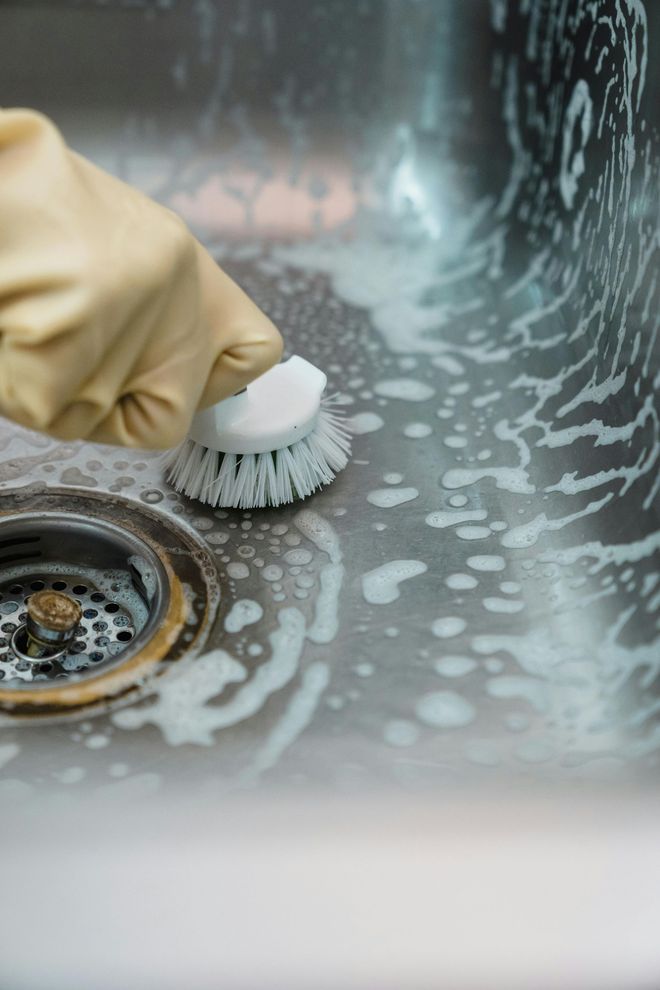 Scrubbing a stainless steel kitchen sink. Scrubbing a stainless steel kitchen sink.