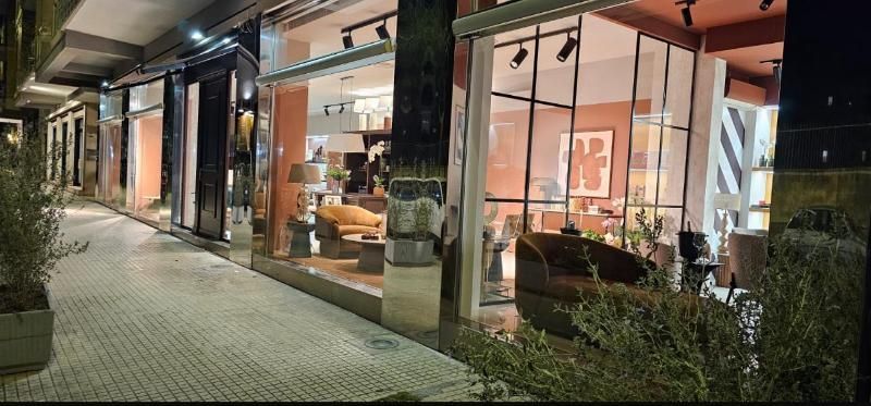 Ristorante moderno con facciata in vetro, illuminato di sera da una calda luce interna e con un marciapiede esterno.