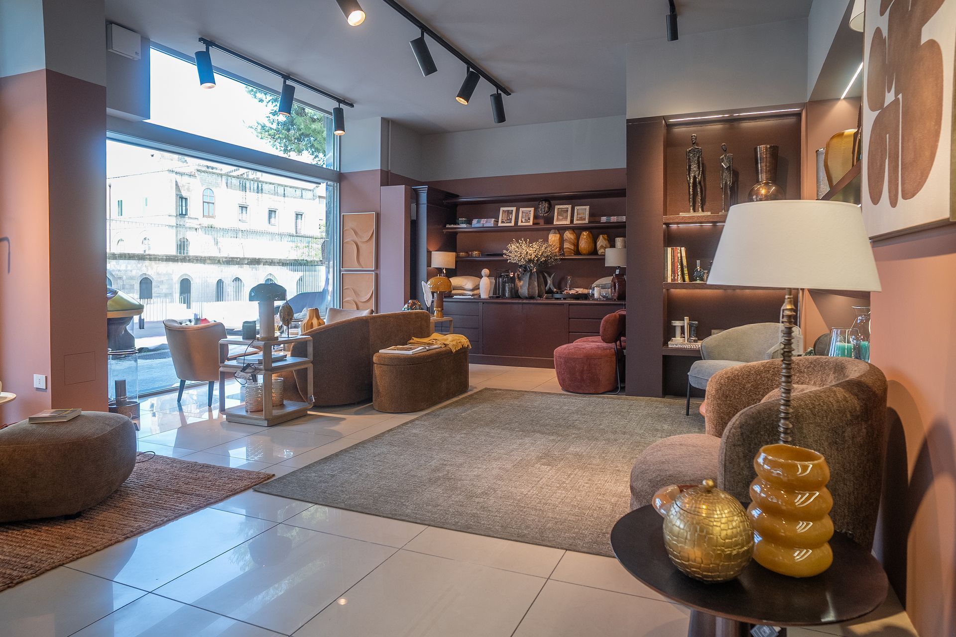 Interno moderno di un salotto con divani, lampade e un'ampia finestra che si affaccia sulla strada.