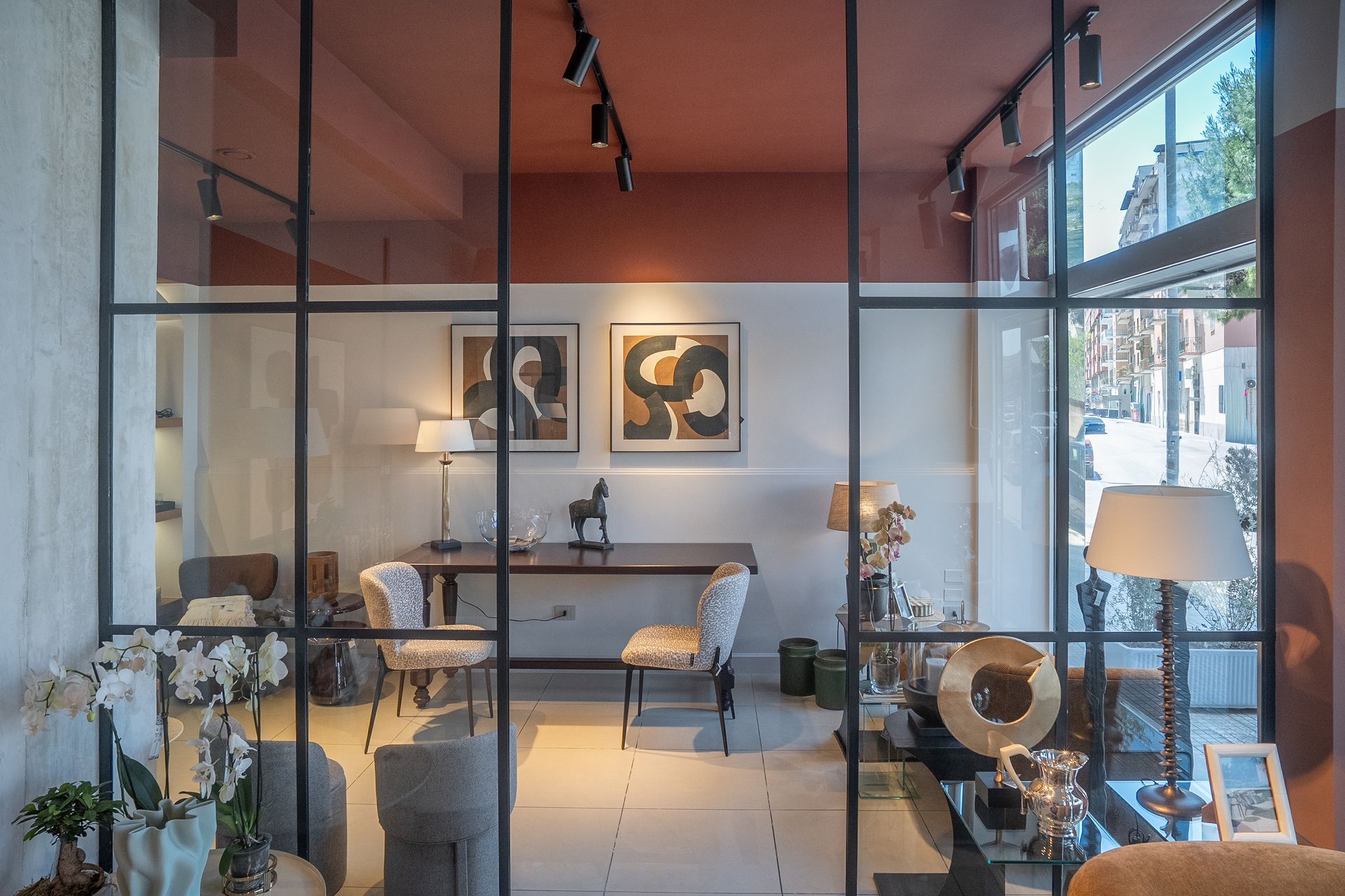 Soggiorno moderno con parete in vetro, illuminazione calda e arredamento minimalista.