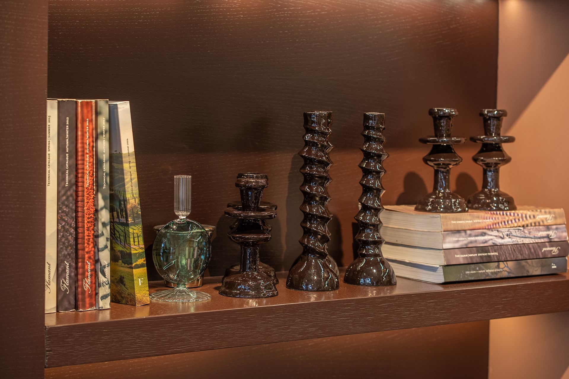 Mensola decorativa con libri impilati, pezzi degli scacchi in vetro e una scacchiera in legno scuro.