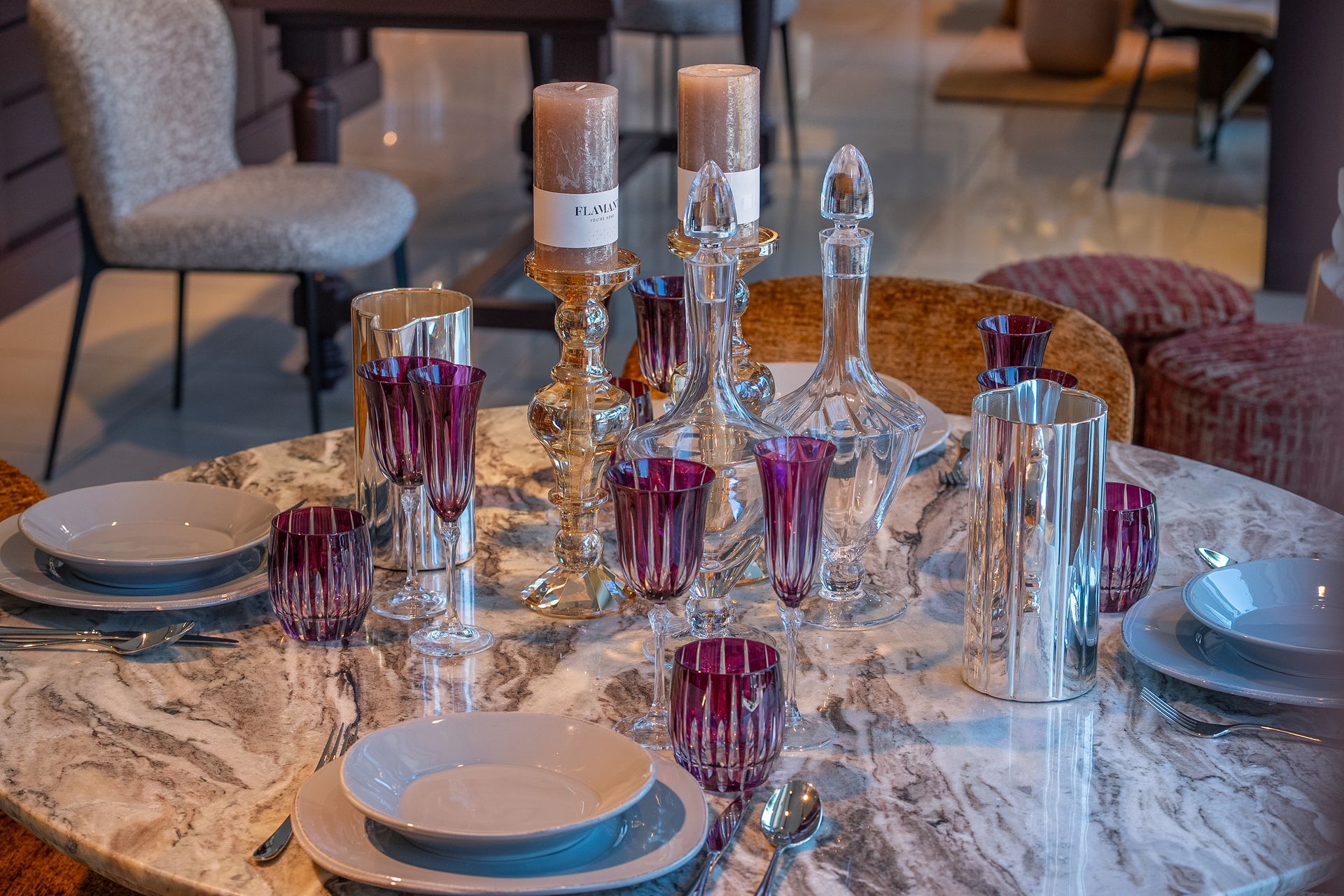 Elegante tavolo da pranzo apparecchiato con candelabri di cristallo, bicchieri viola e piatti bianchi in una stanza accogliente