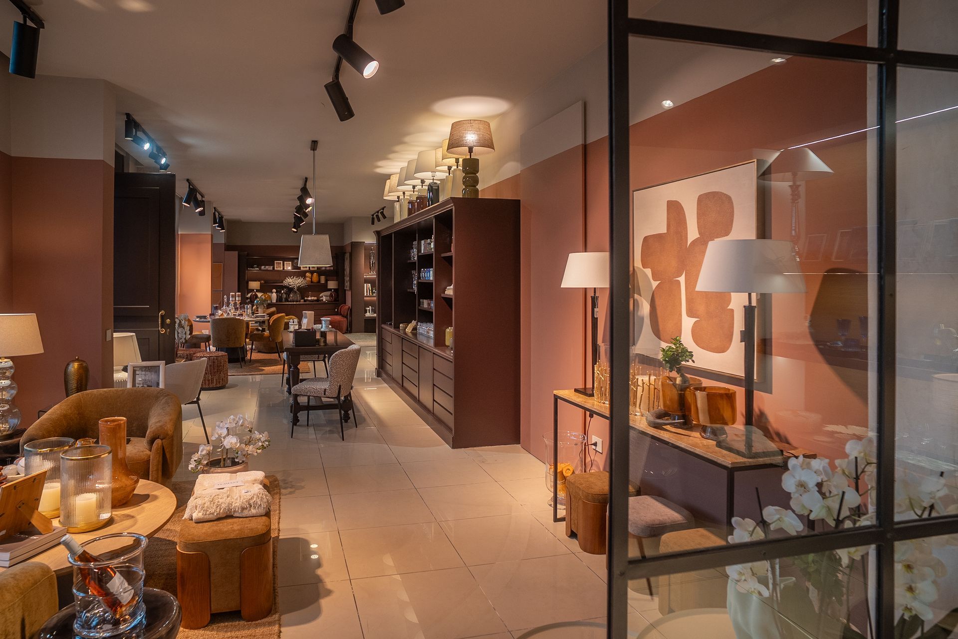 Showroom di mobili moderni con divani, tavoli, lampade e opere d'arte da parete in un'illuminazione calda.