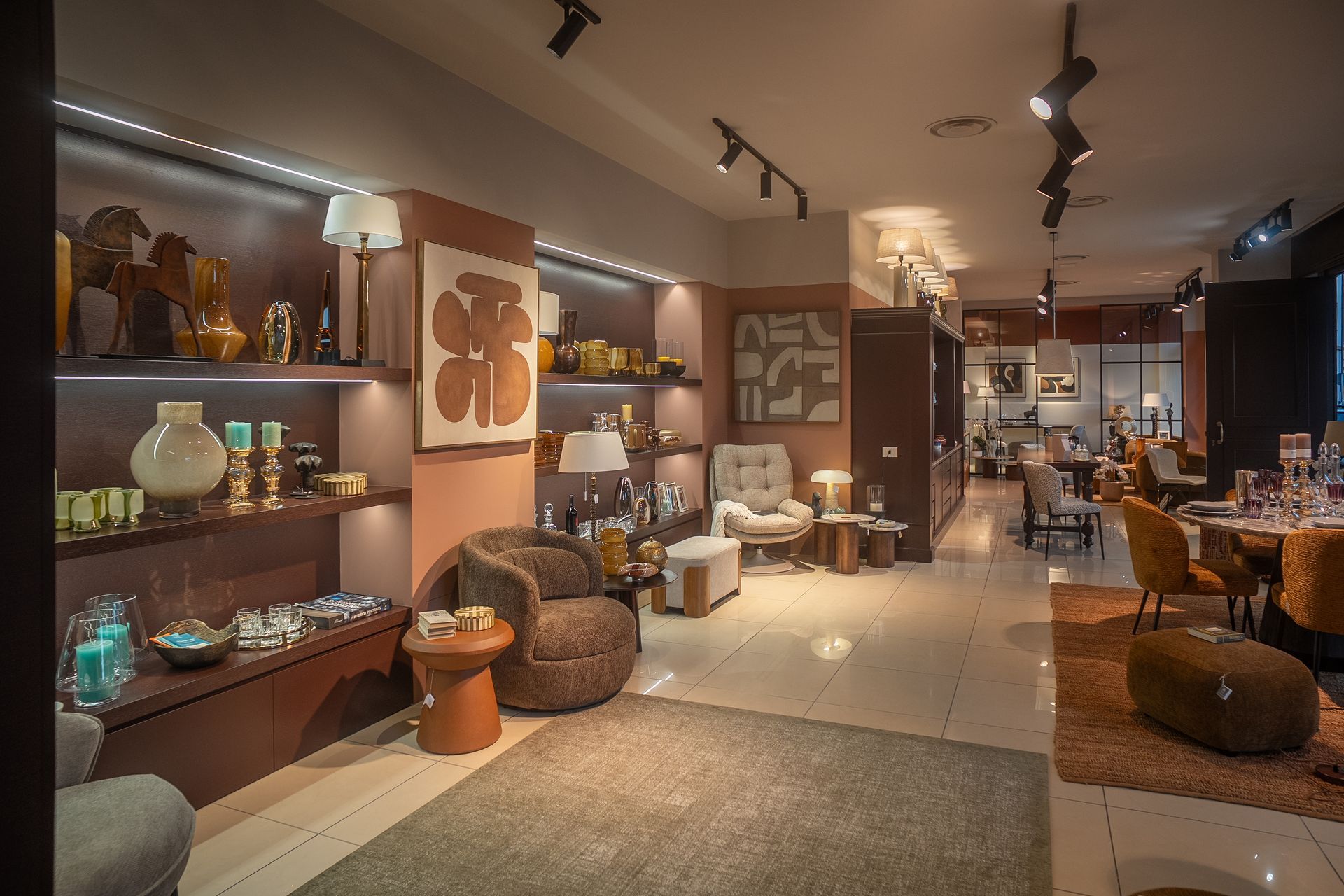 Showroom di mobili moderni con illuminazione calda, scaffali pieni di oggetti decorativi, sedie e tavoli.