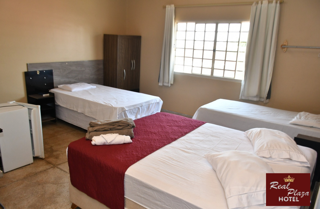 Um quarto de hotel com três camas e uma geladeira