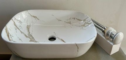 Lavabo de encimera con diseño de mármol y blanco, con desagüe y grifería.
