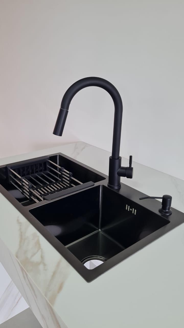 Fregadero de cocina negro con escurridor incorporado y grifo negro mate, colocado en encimera blanca.