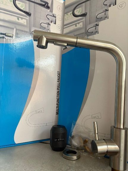 Grifo de cocina de acero inoxidable con rociador extraíble y manija cilíndrica, parcialmente ensamblado.