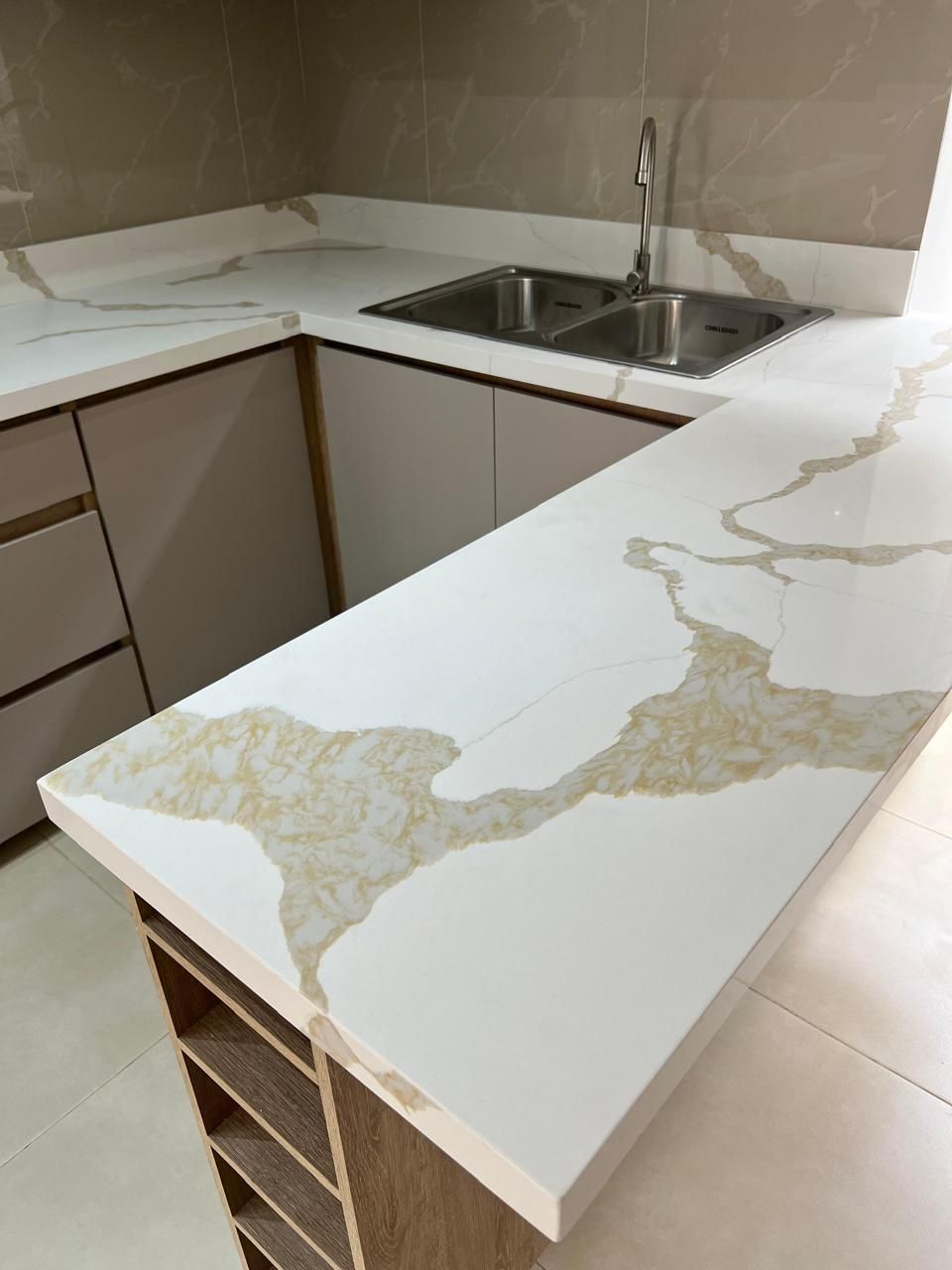 Cocina moderna con encimeras de cuarzo blanco y vetas doradas.