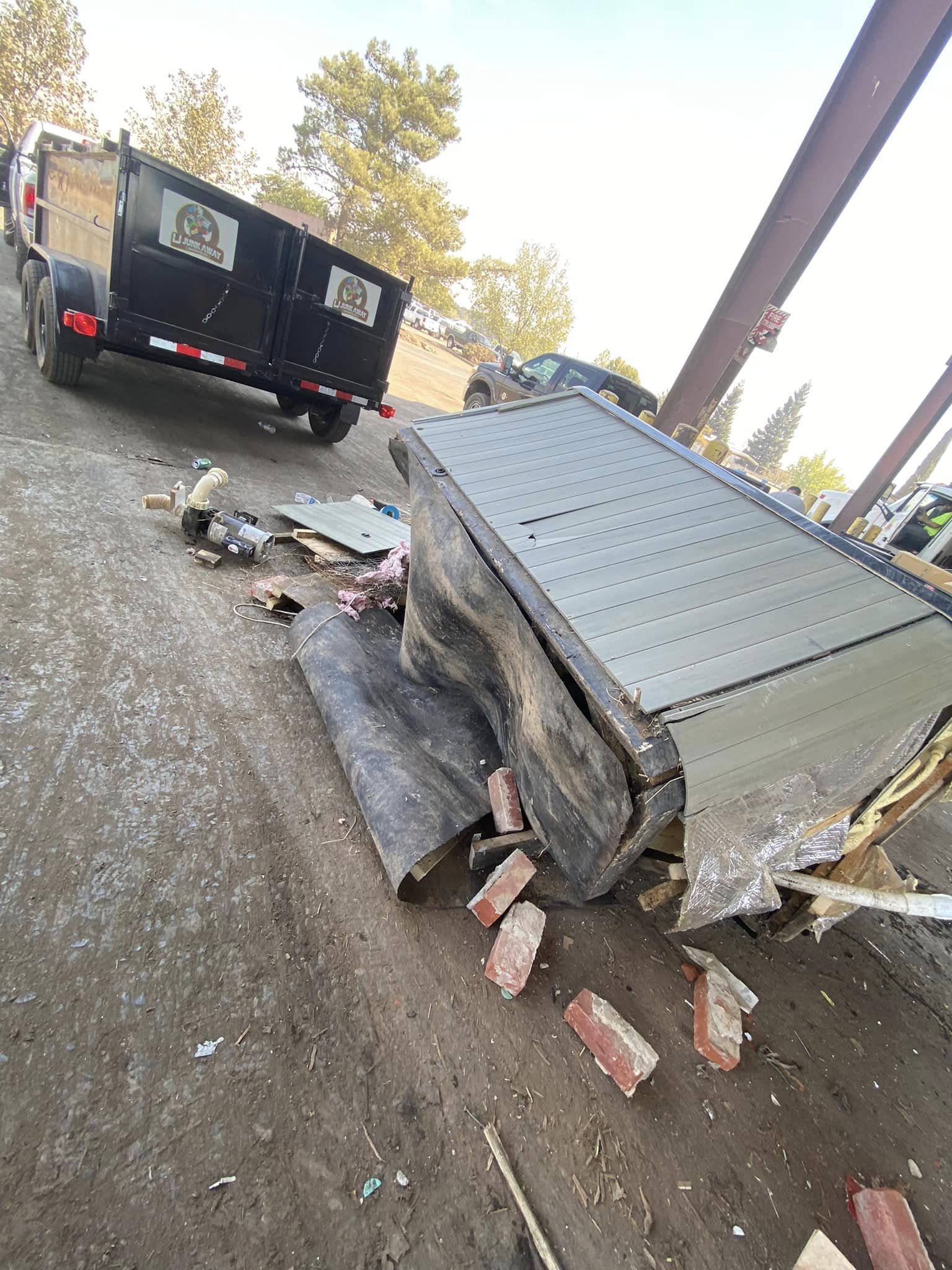 Overturned gray trailer with debris on roadside beside a black truck under an overpass
