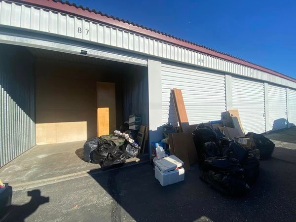 Outdoor loading dock with piles of bags, boxes, and debris beside a warehouse bay.