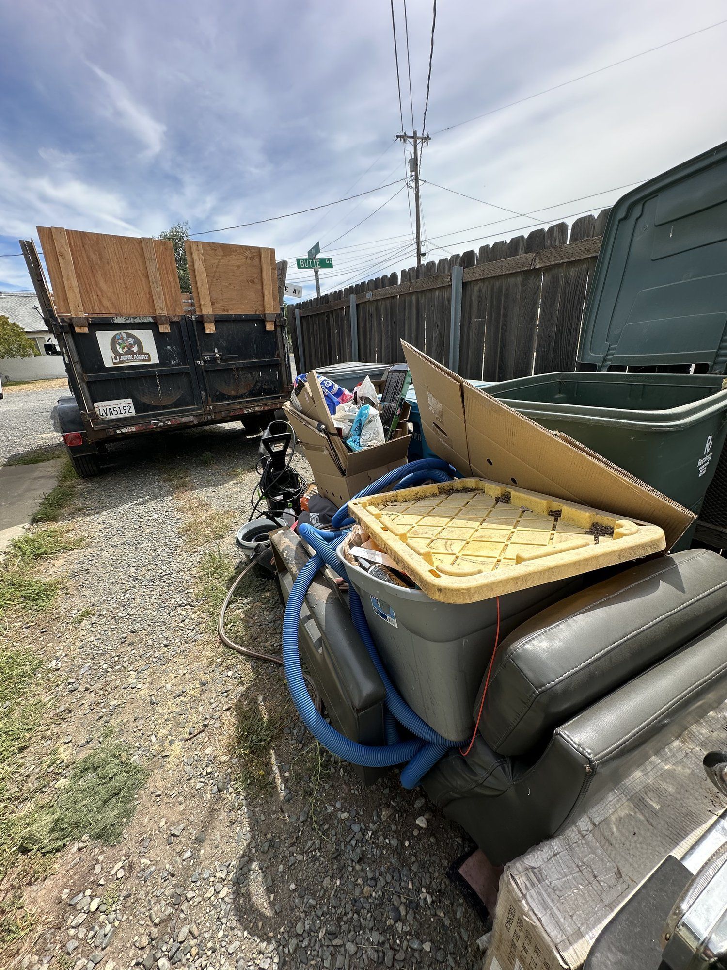 Loaded junk trailer with furniture and debris behind a pickup truck
