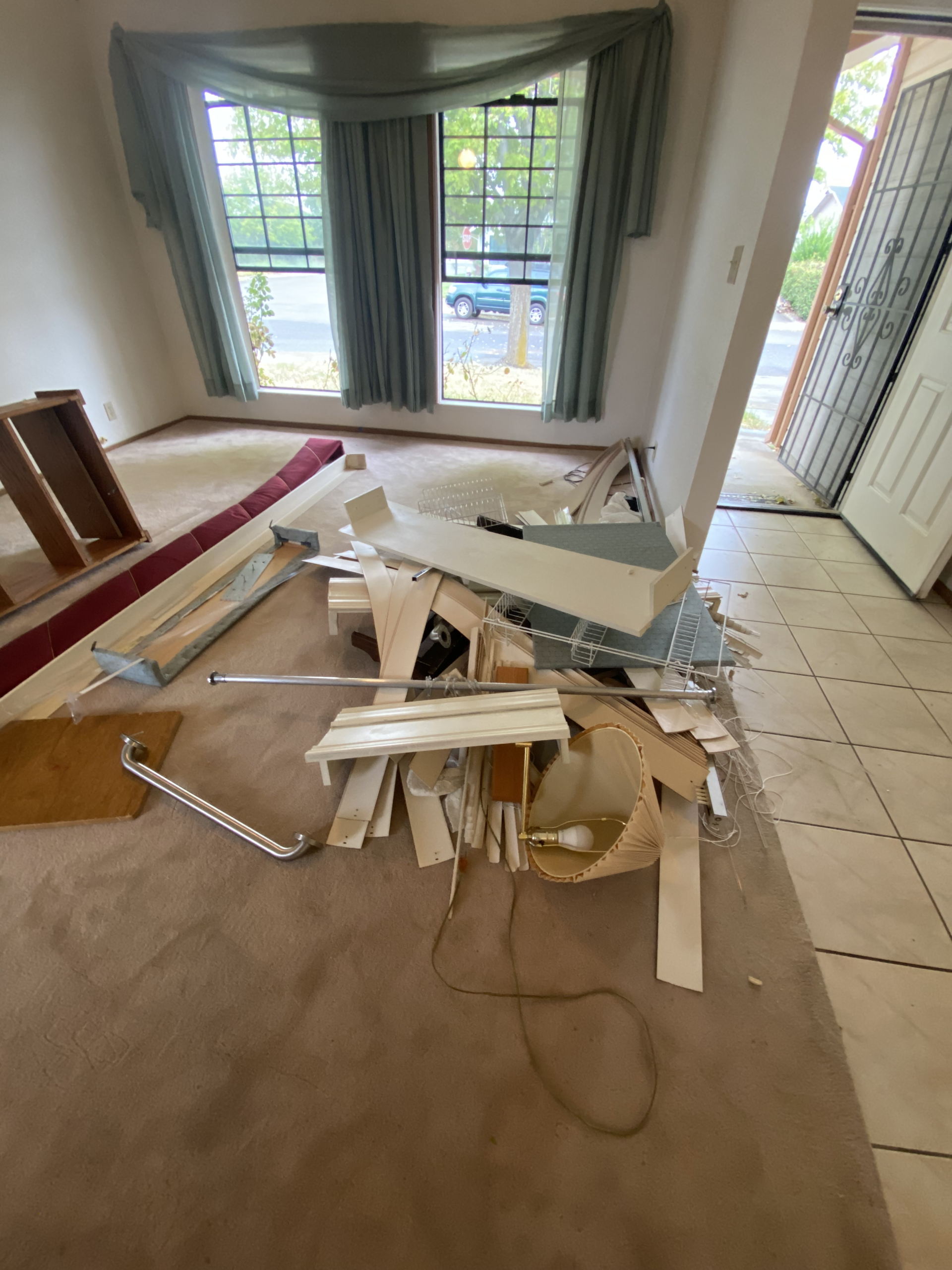 Damaged room with broken ceiling debris scattered across the floor near windows and a doorway