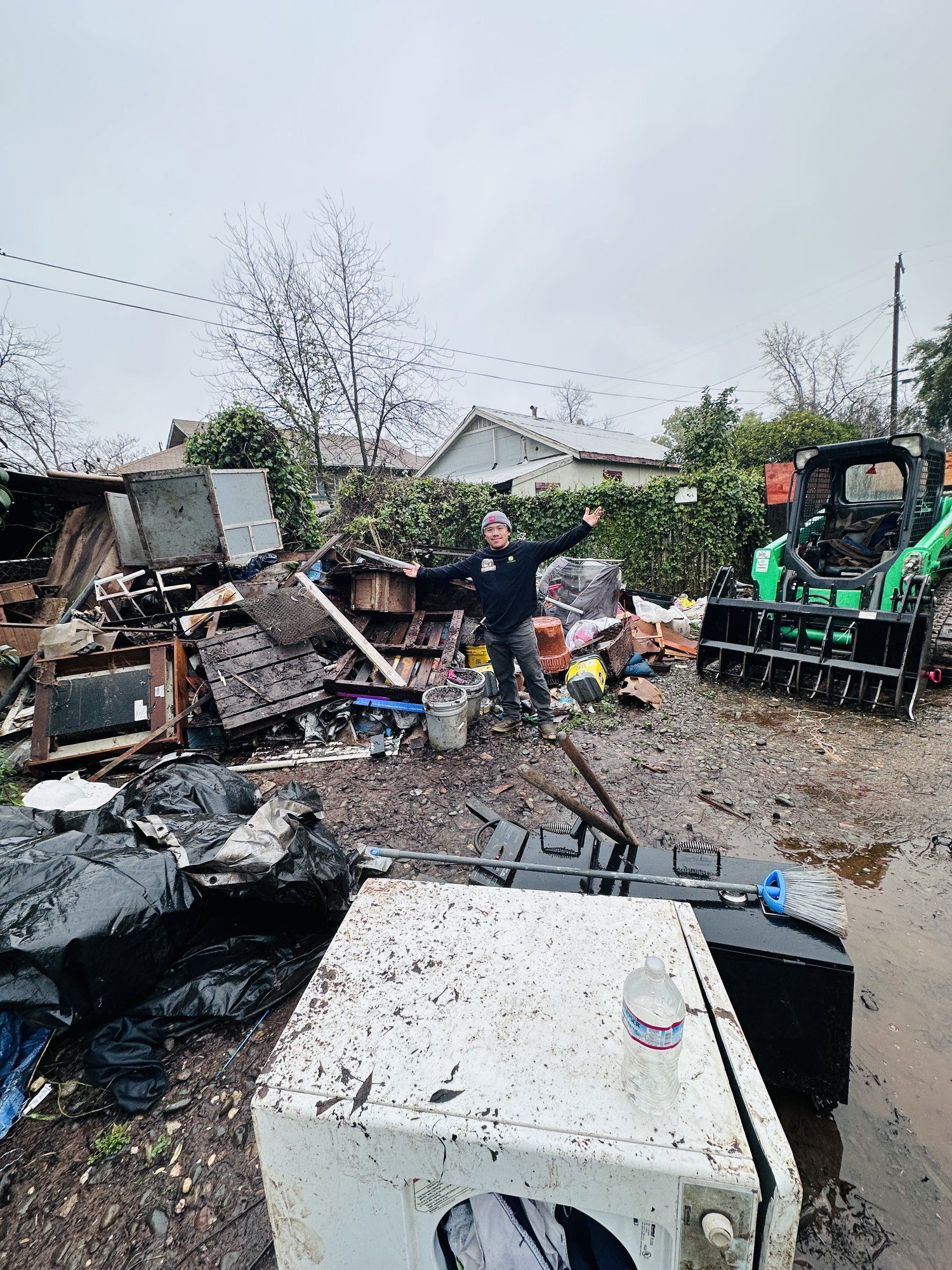 LJ Junk Away crew using a skid steer to clear a backyard full of debris