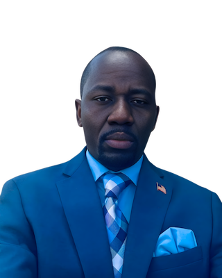 Man in a blue suit and tie, looking directly at the camera. He has a serious expression.