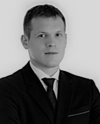 Mężczyzna w garniturze i krawacie, patrzący przed siebie, portret studyjny.