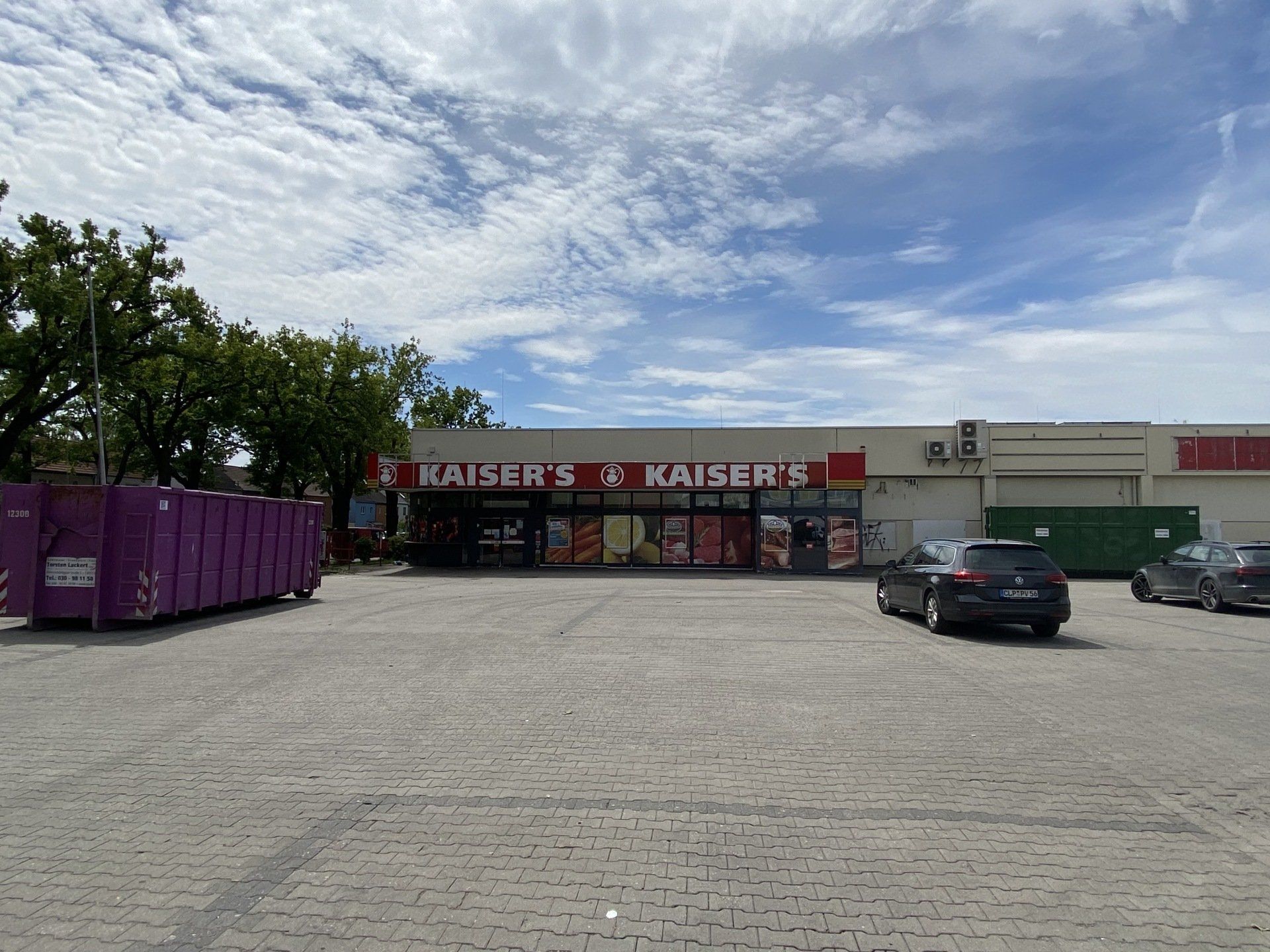 曇り空の下の、看板、入り口、駐車した車があるカイザー食料品店の正面。