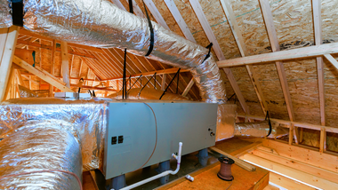 Technician connecting hoses to an outdoor air-conditioning unit with tools and gauges