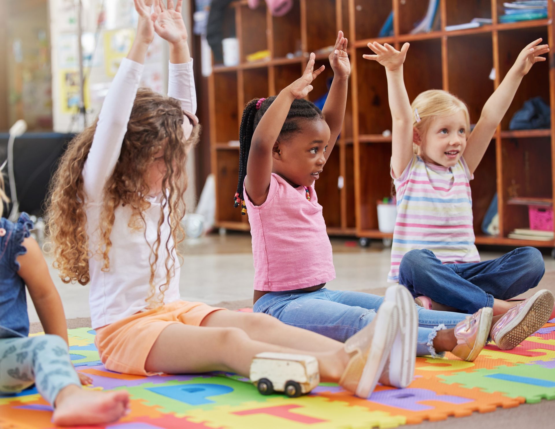 A group of toddlers is raising their hands.