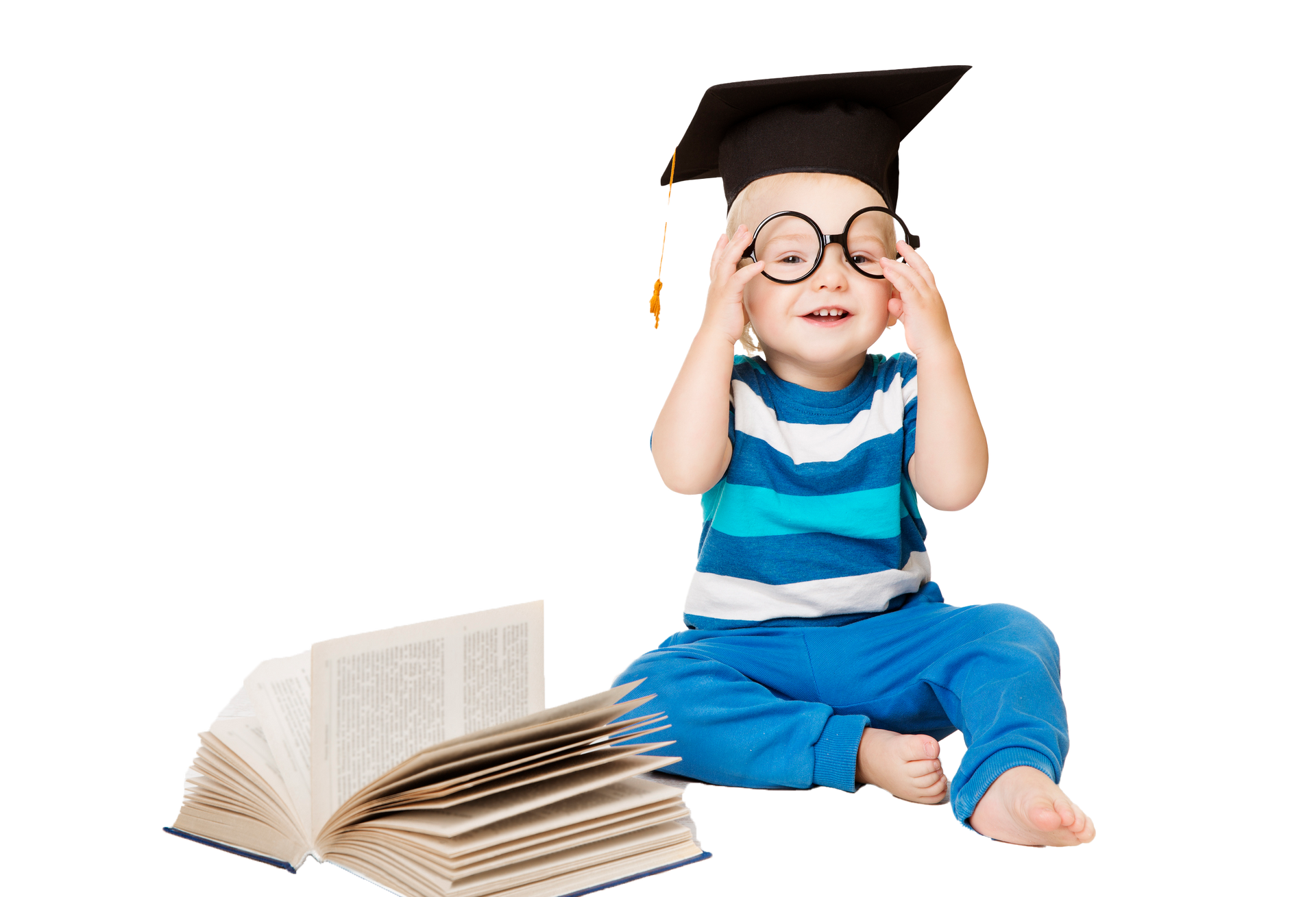 A toddler in graduation cap and glasses, laughing, sitting near an open book. Smiling baby wearing graduation cap and glasses, sitting by an open book.