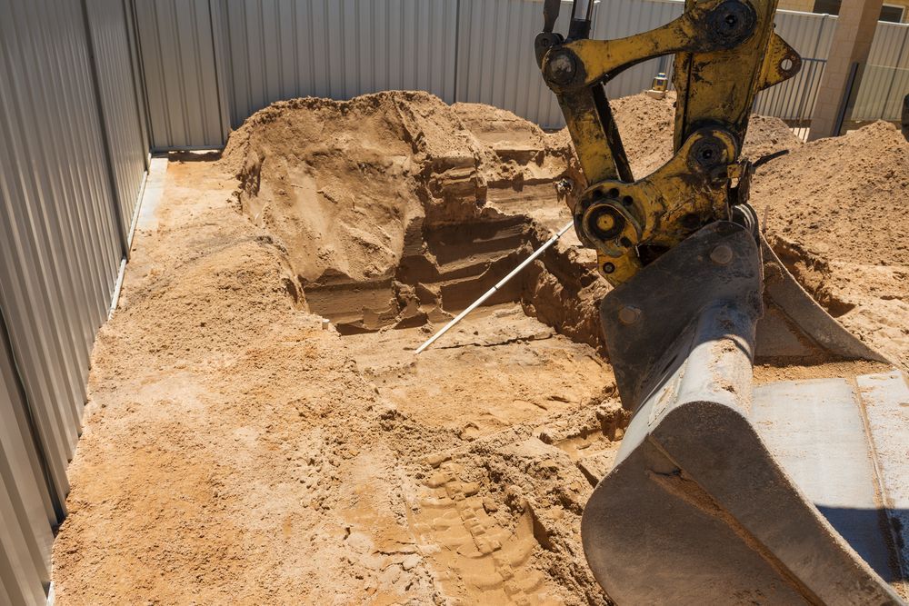 A Yellow Excavator Is Digging A Hole In The Dirt — Territory Industries Pty Ltd In Katherine, NT