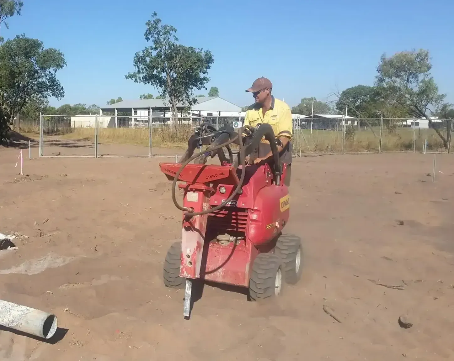 A Man Is Using A Red Tractor In A Dirt Field — Territory Industries Pty Ltd In Uralla, NT