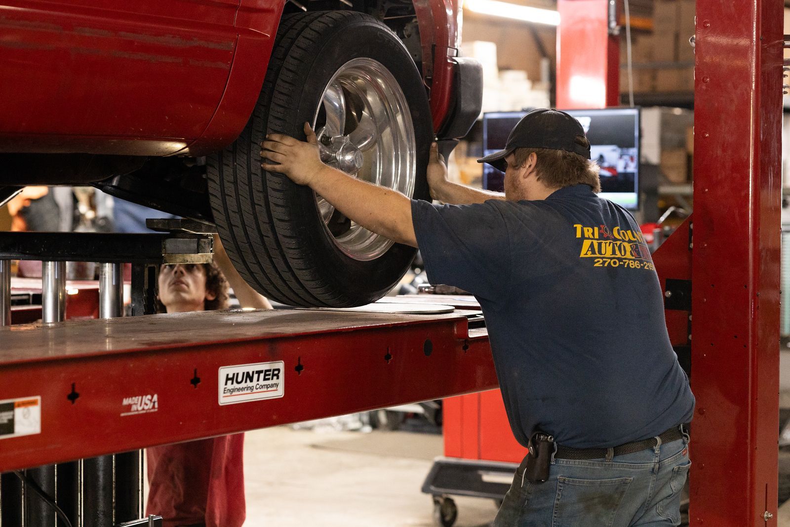 A service mechanic is working on a car on a lift in a garage.