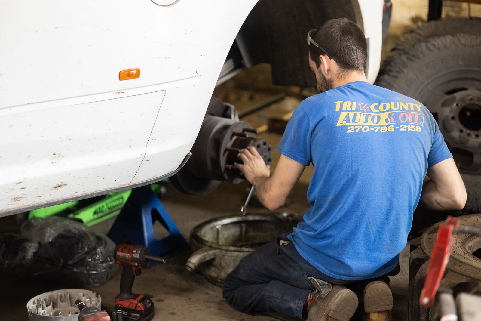A service mechanic is working on a car in a garage.