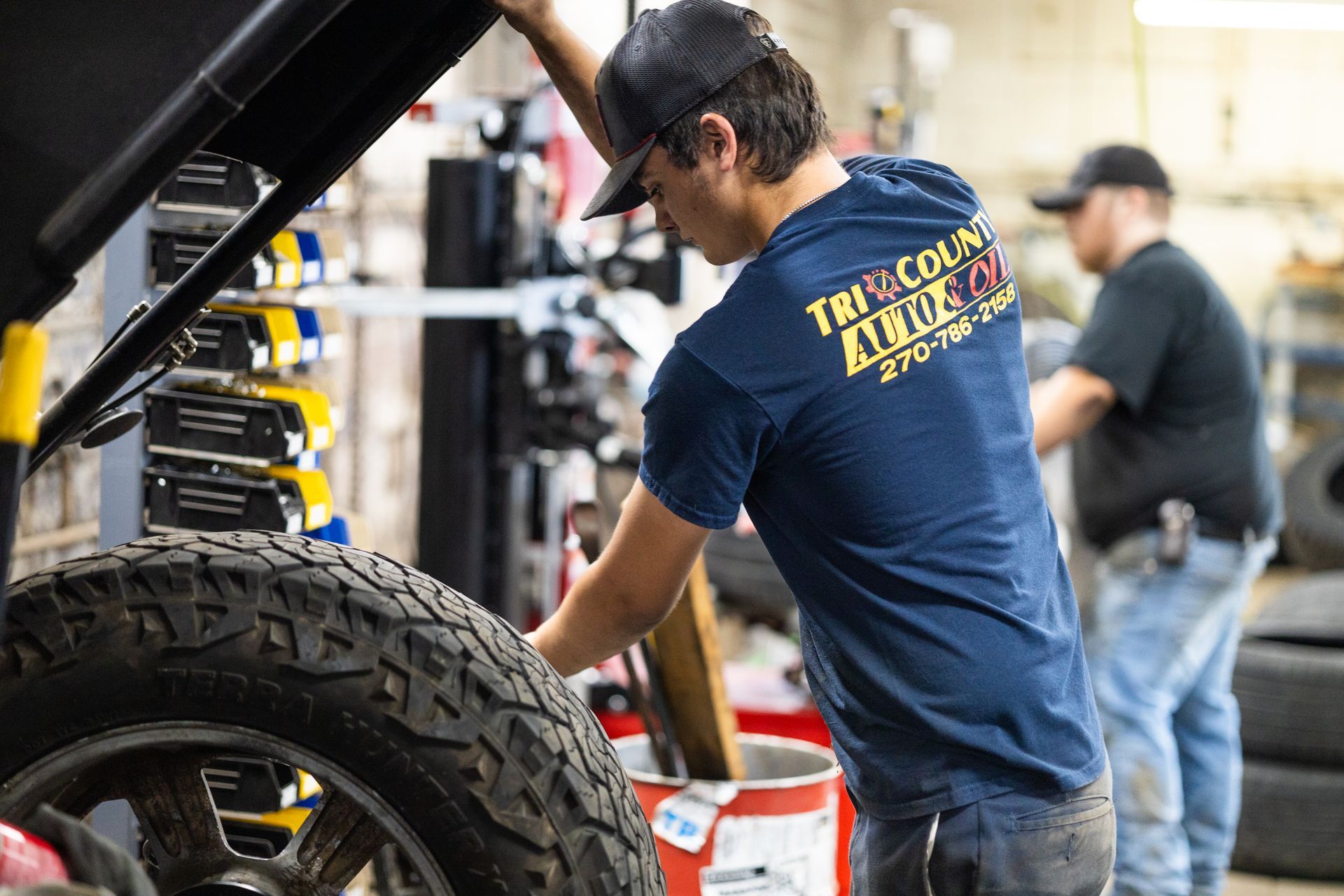 A service mechanic is working on a tire in a garage.