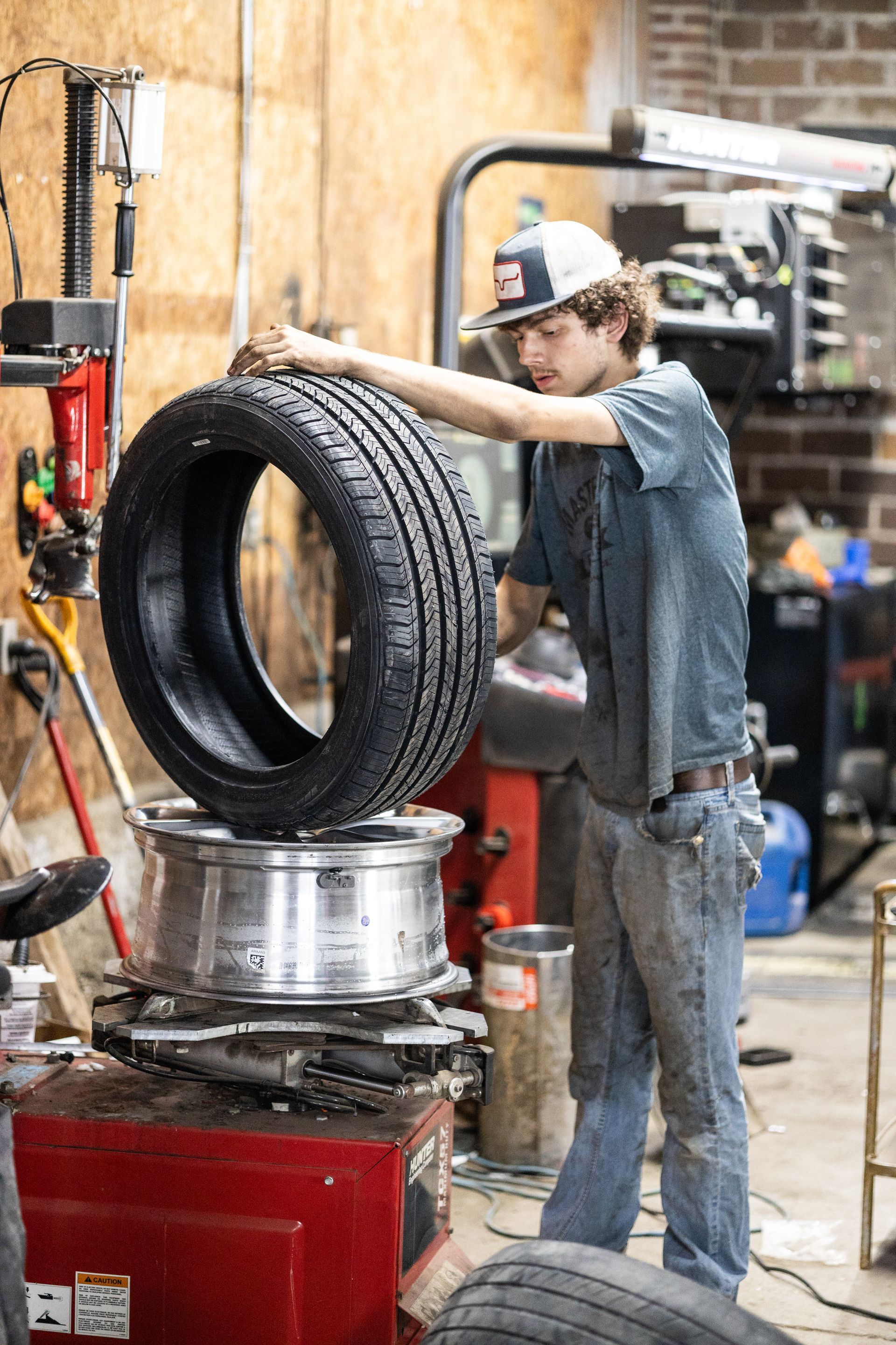 A service mechanic is changing a tire on a machine in a garage.