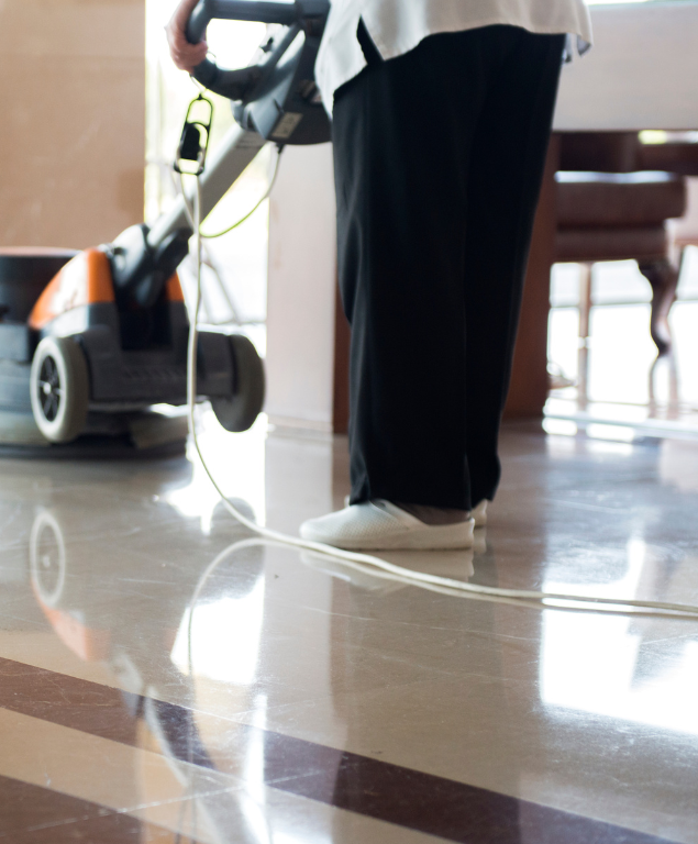 A person is using a vacuum cleaner on a marble floor