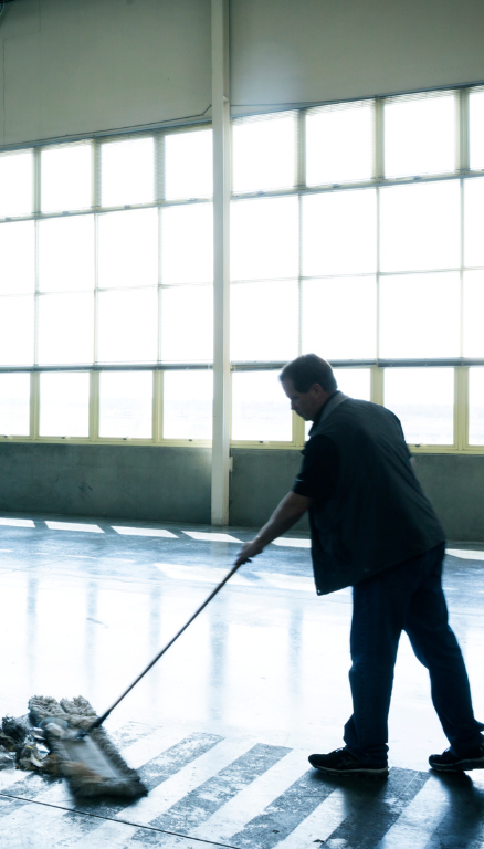 A man is mopping the floor of a building with a mop.