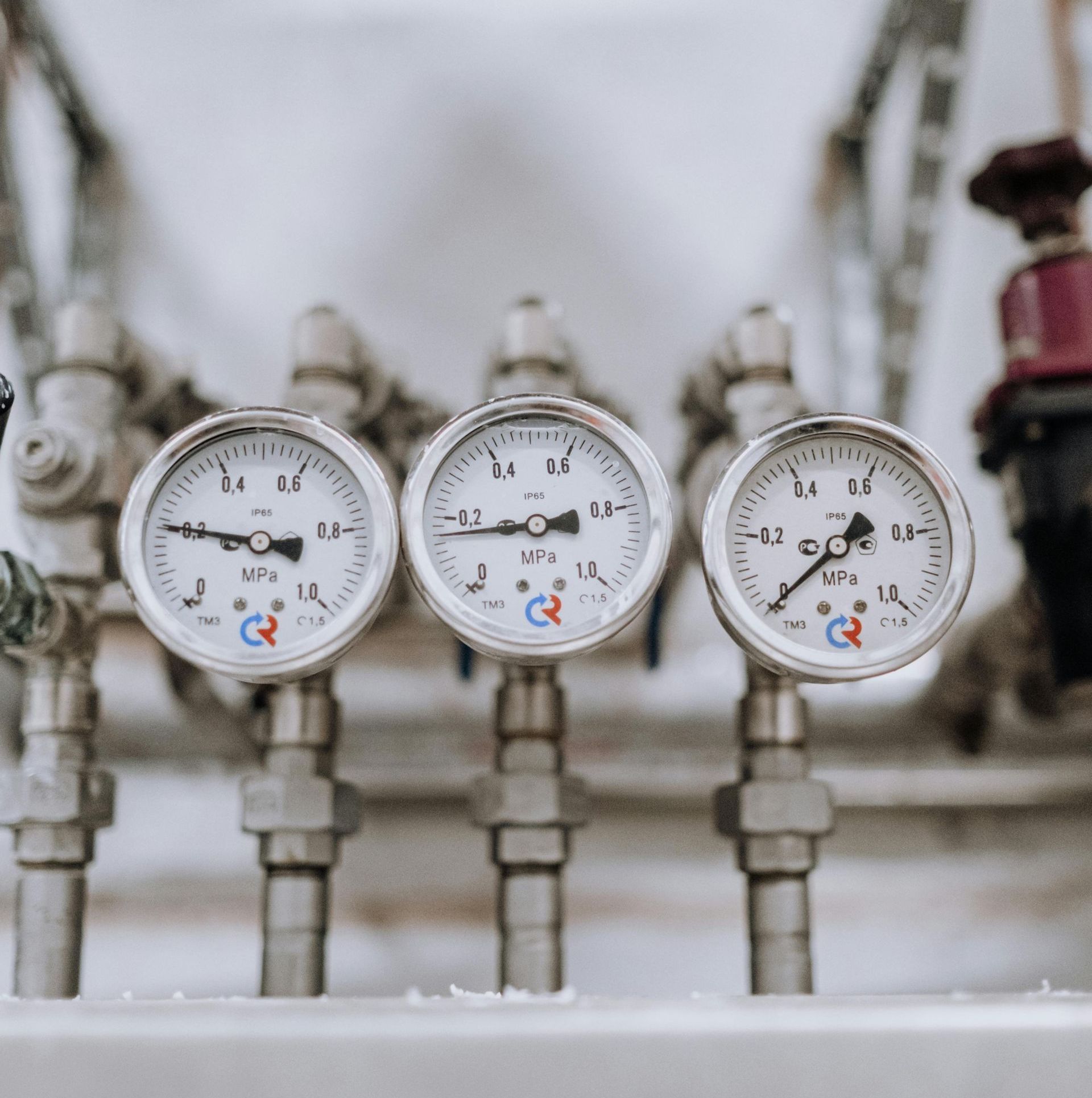 Three pressure gauges are sitting next to each other on a pipe.