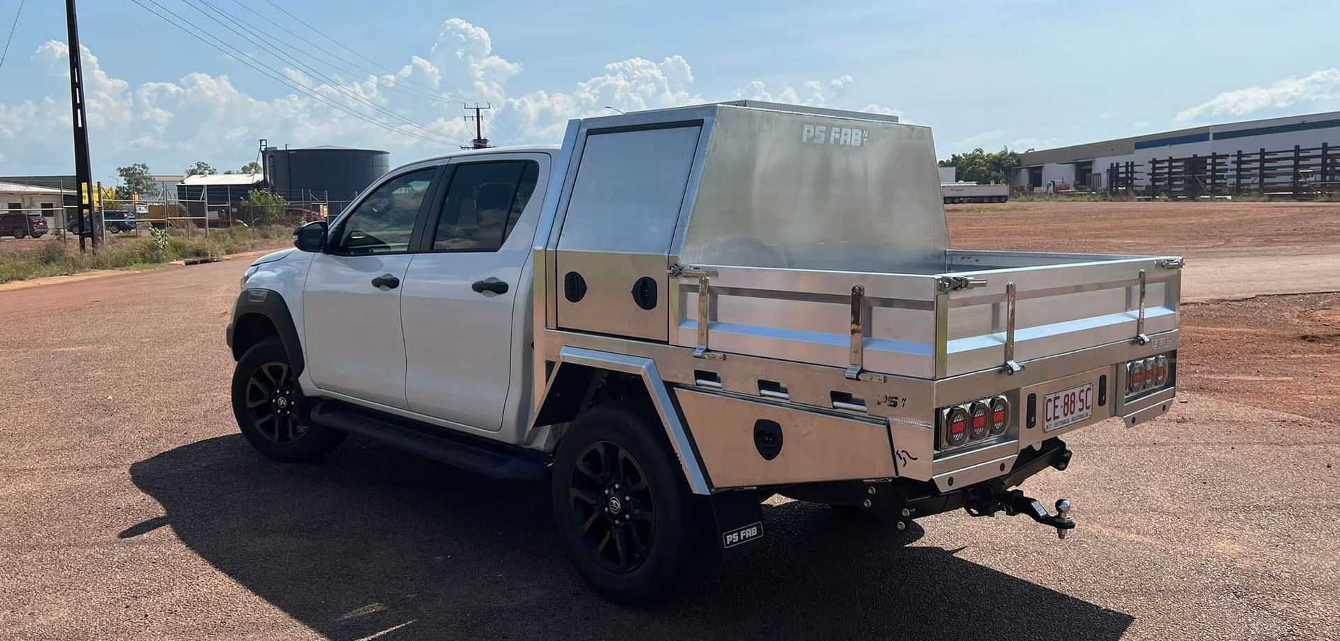 White pickup truck with a silver flatbed parked on a dirt lot under a blue sky