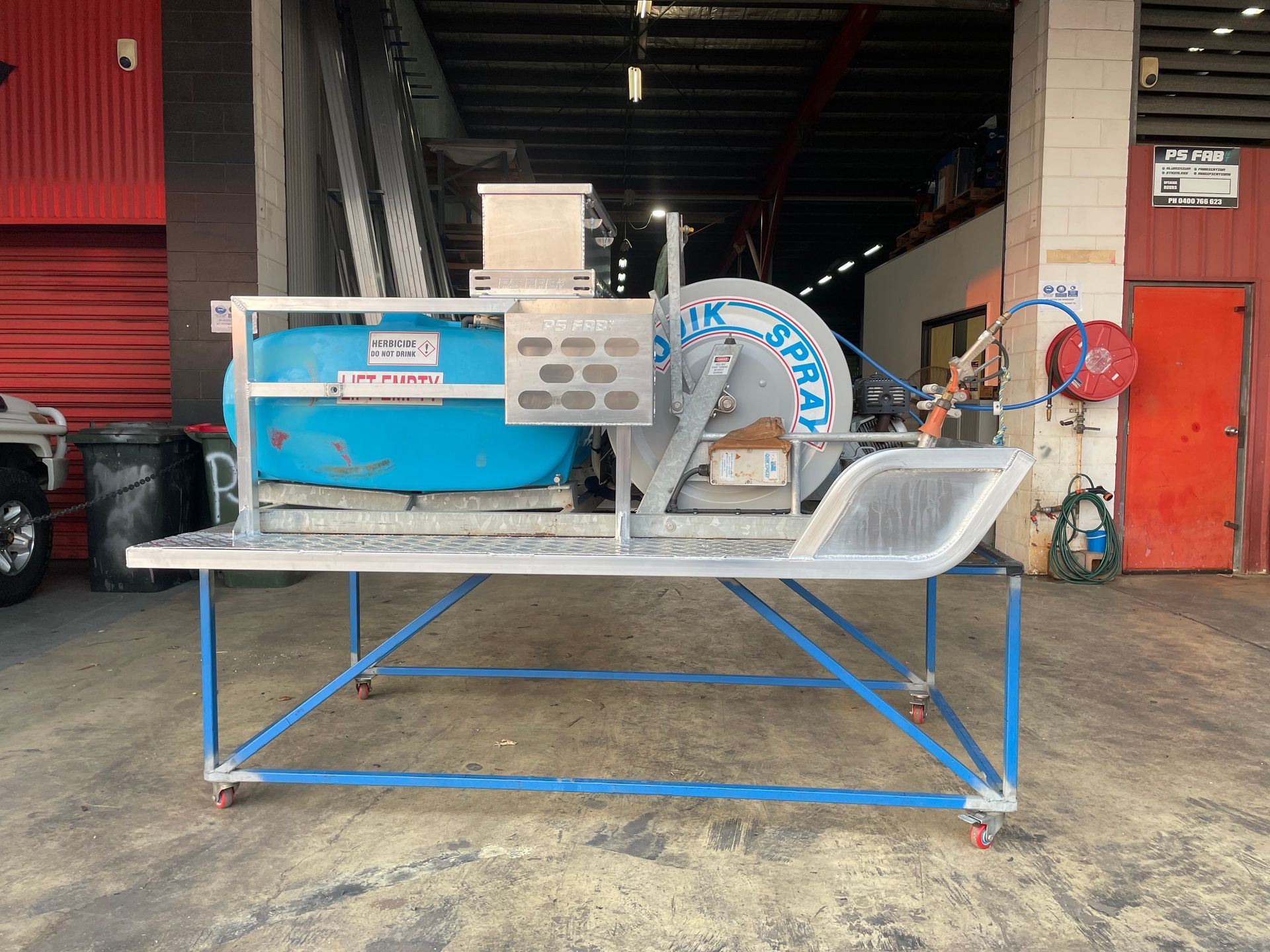 Blue industrial machine on a metal cart in a workshop garage area