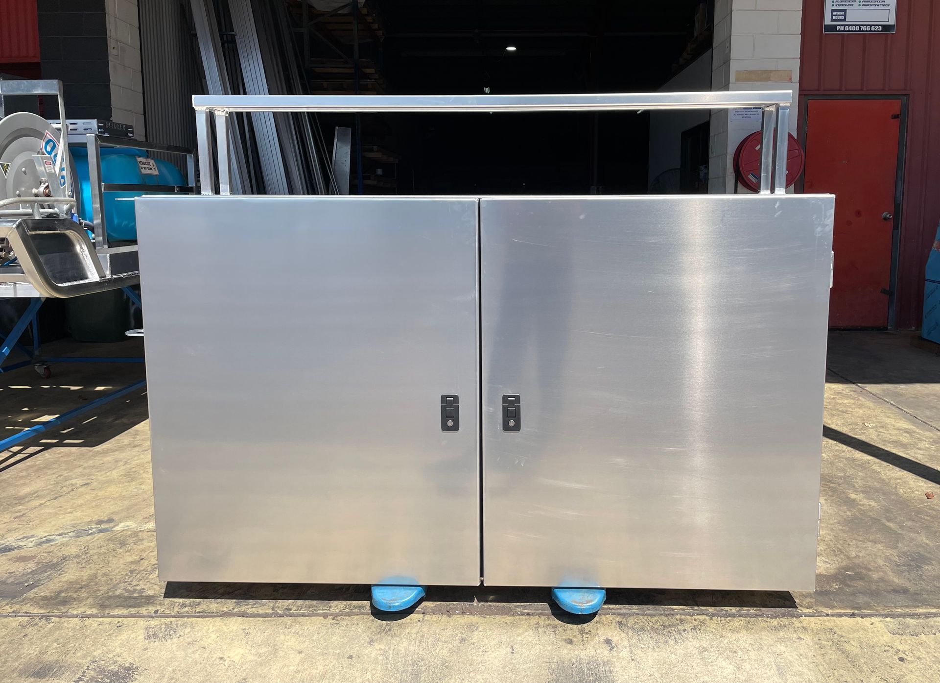 Large stainless steel cabinet with two doors on blue casters in an industrial setting