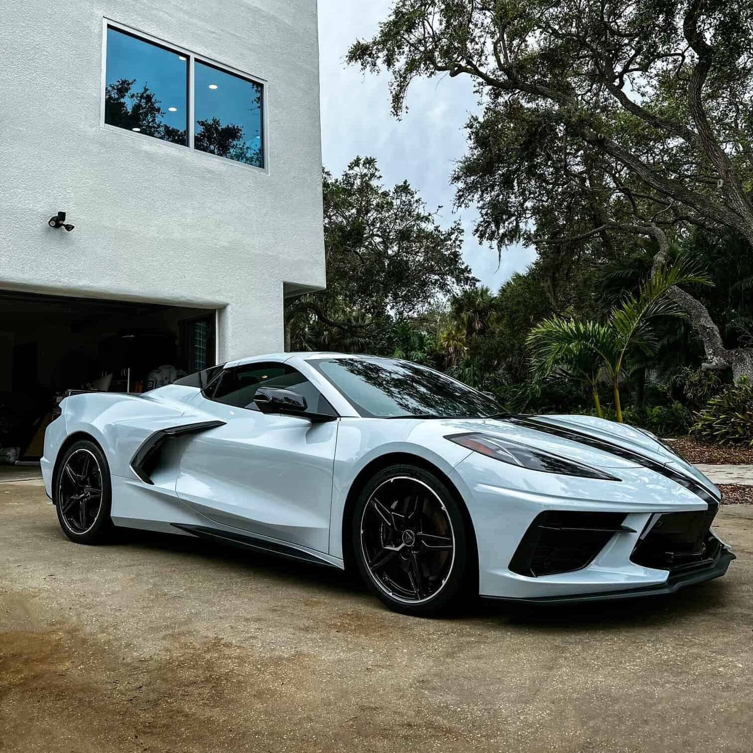 White C8 Corvette Stingray with Palm Trees and a Mansion behind it