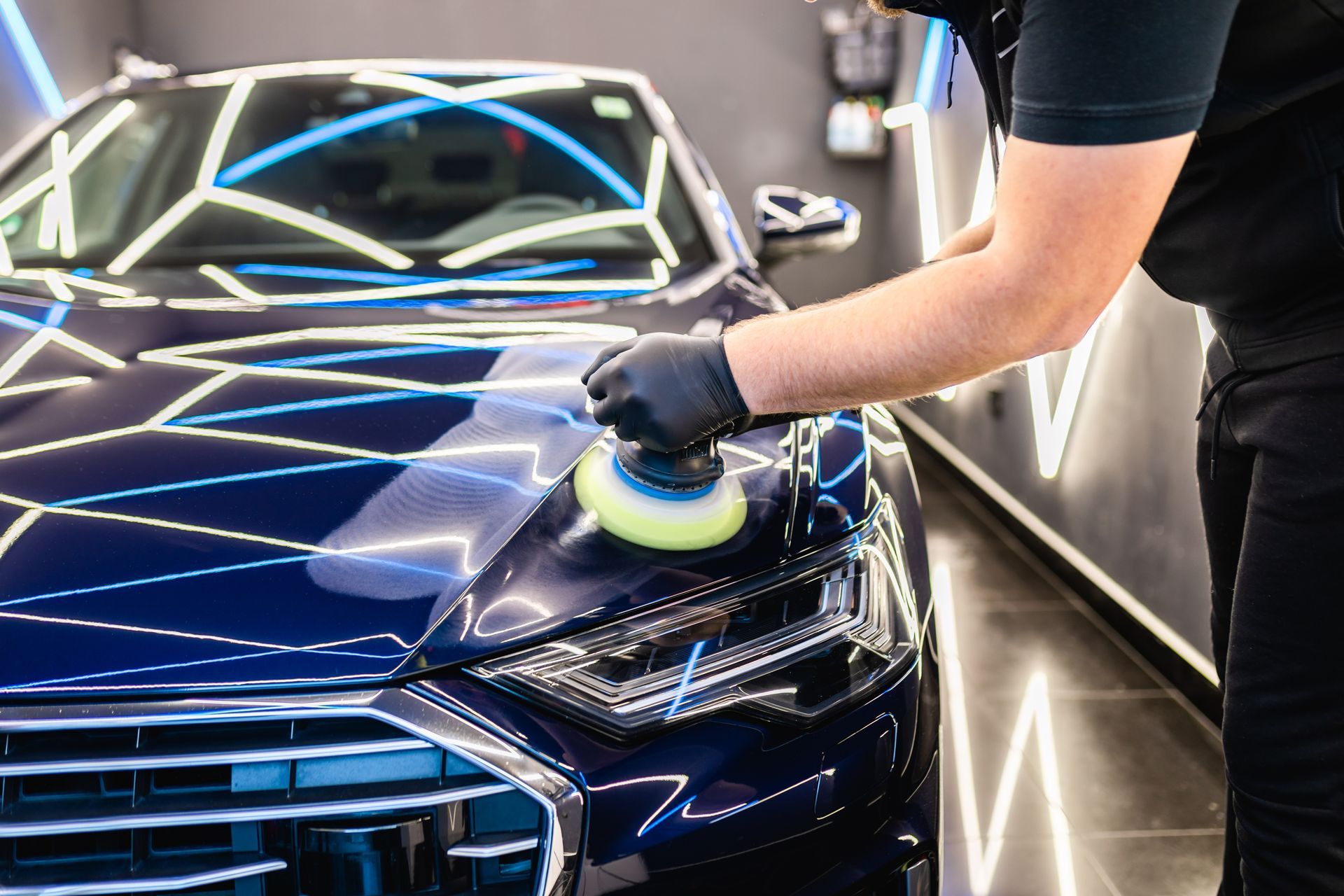Car detailing - Man with Rupes orbital polisher in repair shop polishing car. Selective focus. Polishing a Blue BMW M4