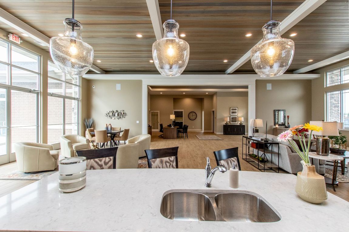Kitchen island and sink overlooking a living space with decorative pendant lights and large windows.