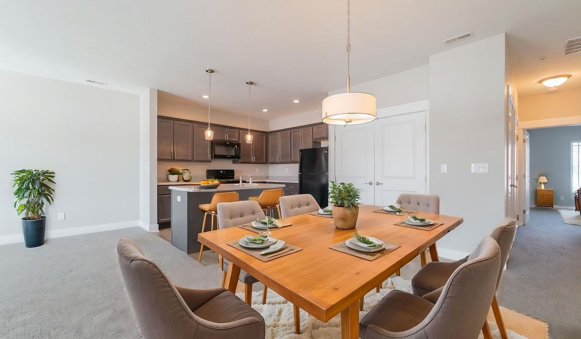 Dining room with wooden table and chairs, open to kitchen with dark cabinets.