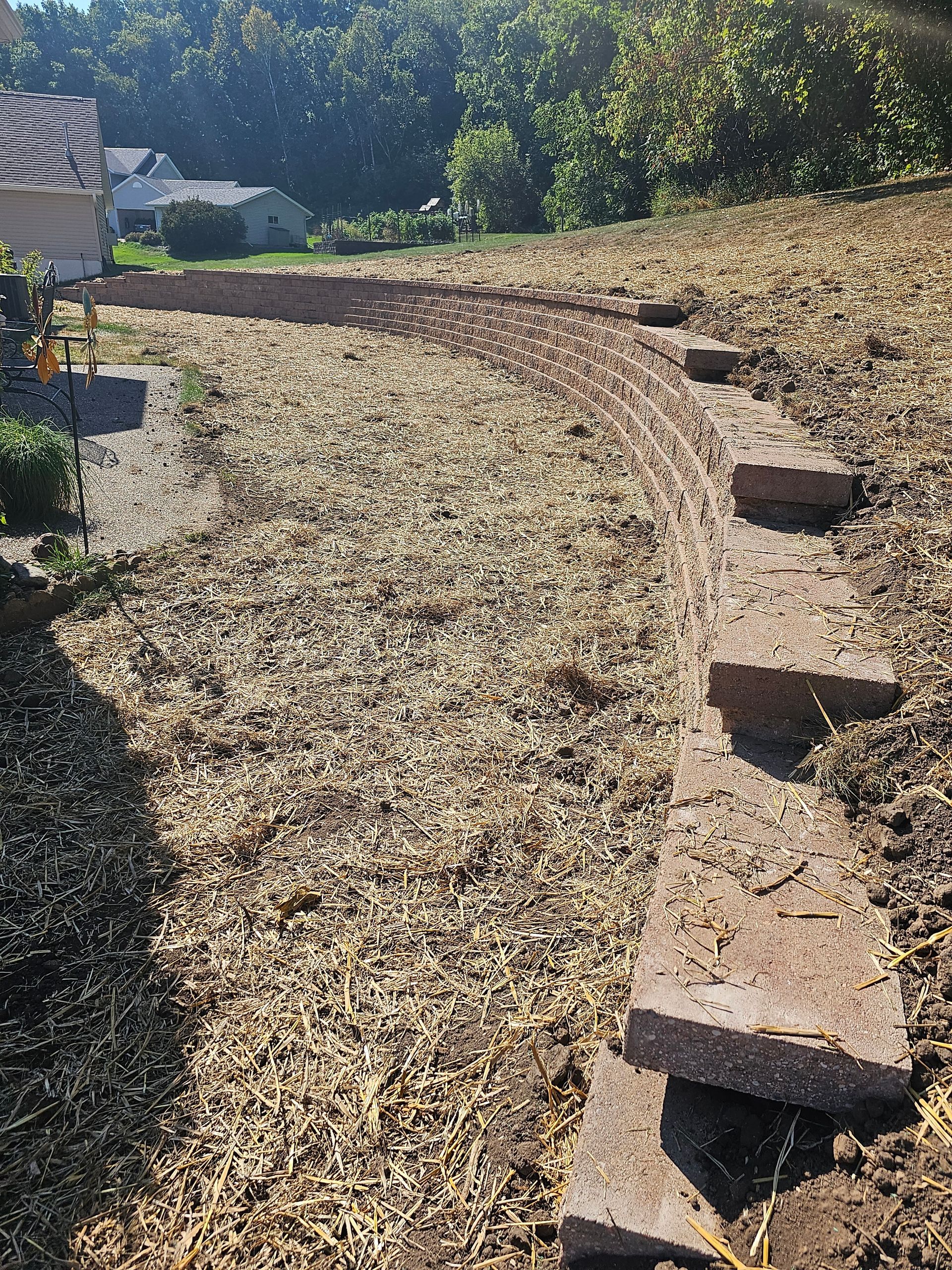 A dirt field with a few steps in it and a house in the background.