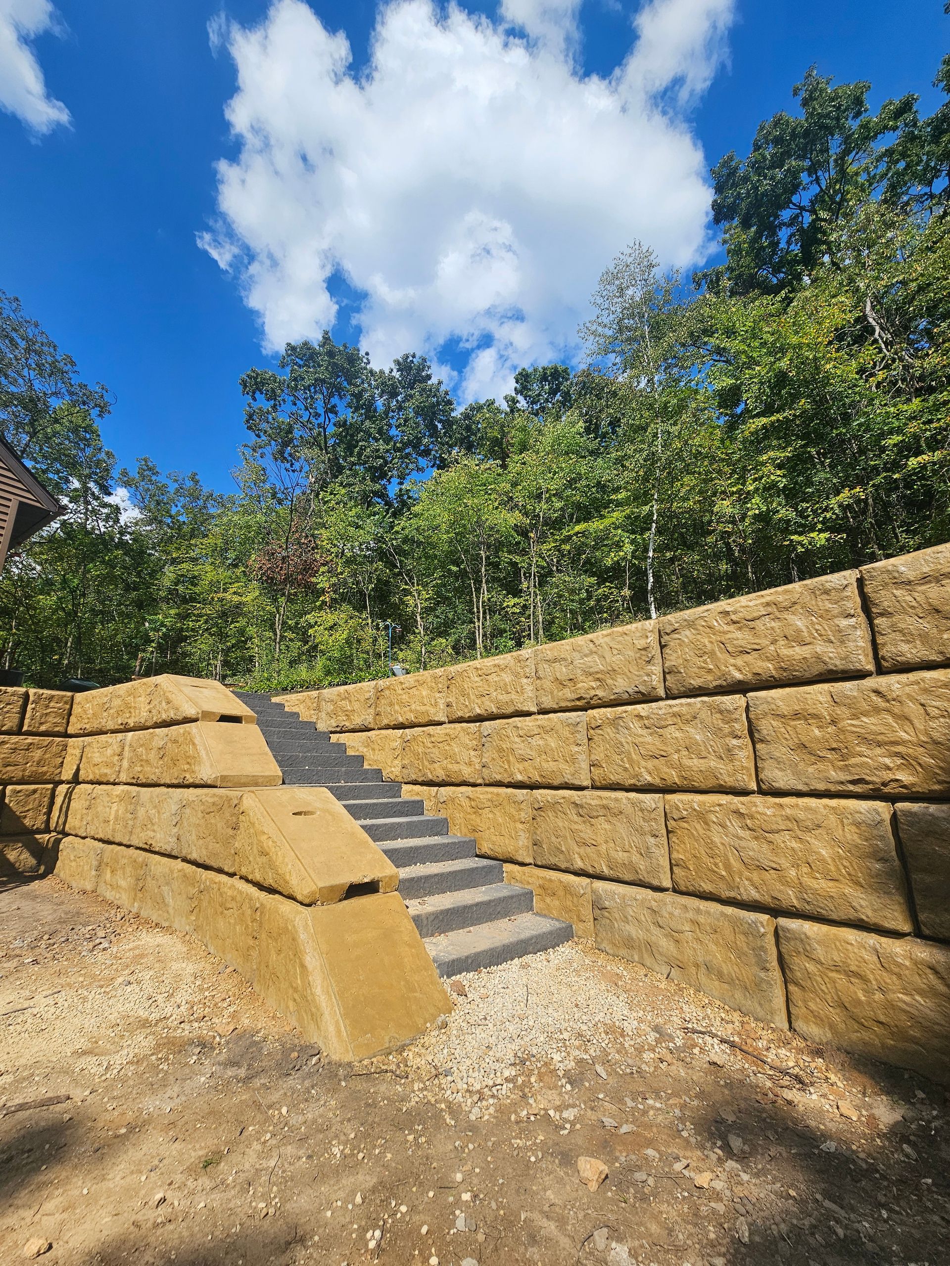 A stone wall with stairs leading up to it and trees in the background.