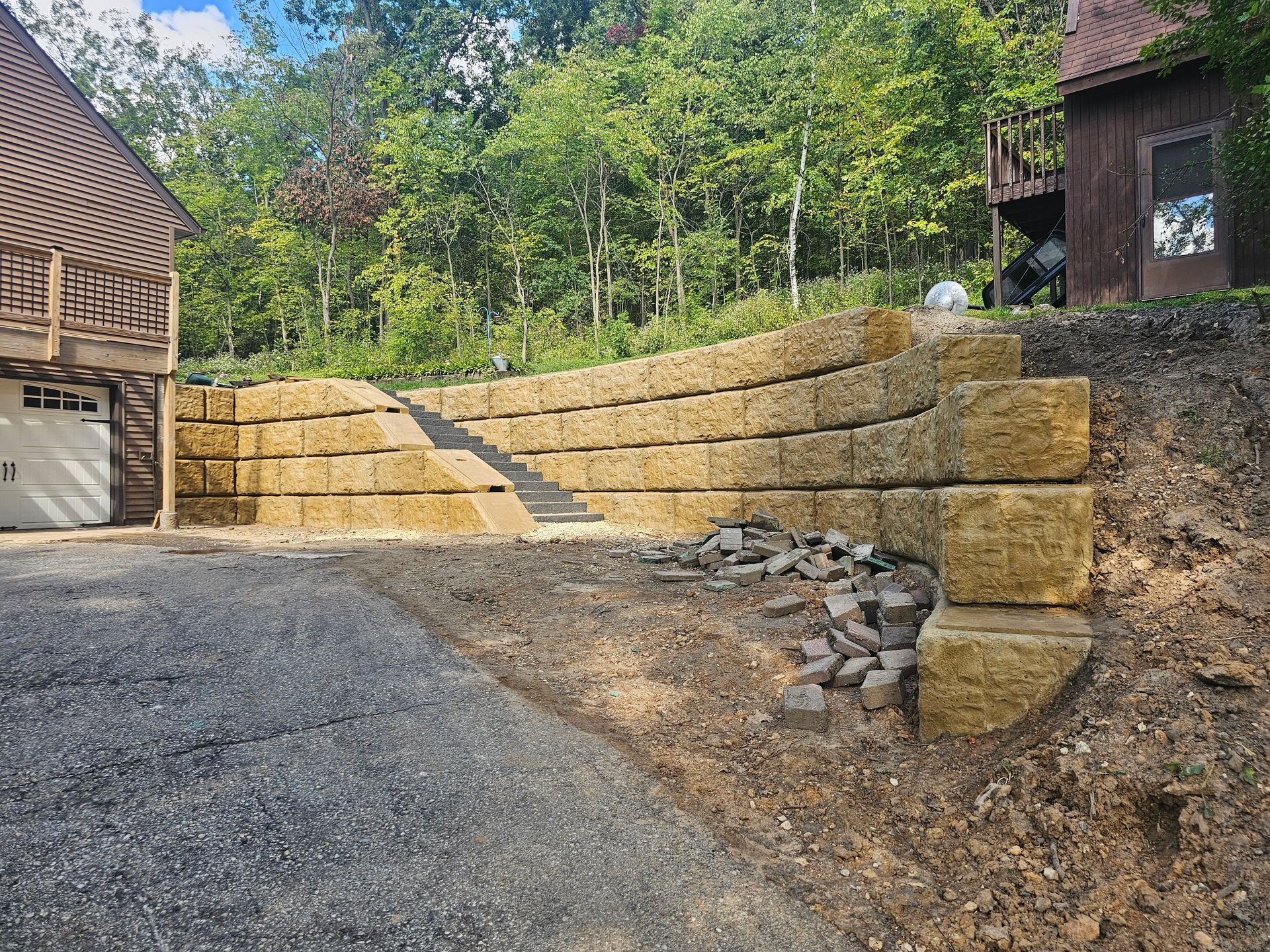 A large stone wall is being built in front of a house.